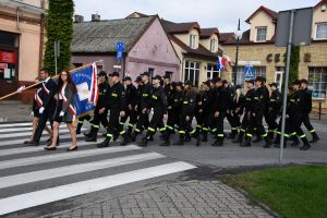 Maszerująca kolumna uczniów w strażackich mundurach