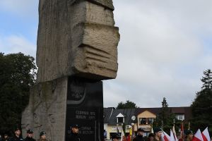 Stojący przed pomnikiem uczniowie w mundurach