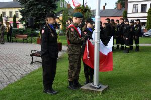 Mężczyzna i dwie kobiety, wciągający flagę na maszt