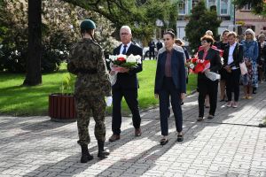 Mężczyzna i kobieta, niosący kwiaty, z przodu kobieta w mundurze