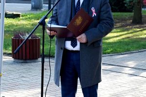 Mężczyzna w płaszczu, mówiący do mikrofonu
