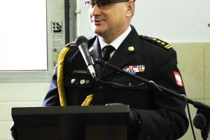 Mężczyzna w strażackim mundurze, mówiący do mikrofonu