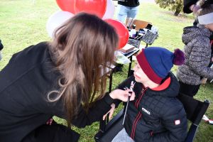 Uczennica maluje dziecku barwy narodowe na twarzy