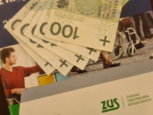 Banknoty stuzłotowe i dokument z logiem ZUS-u